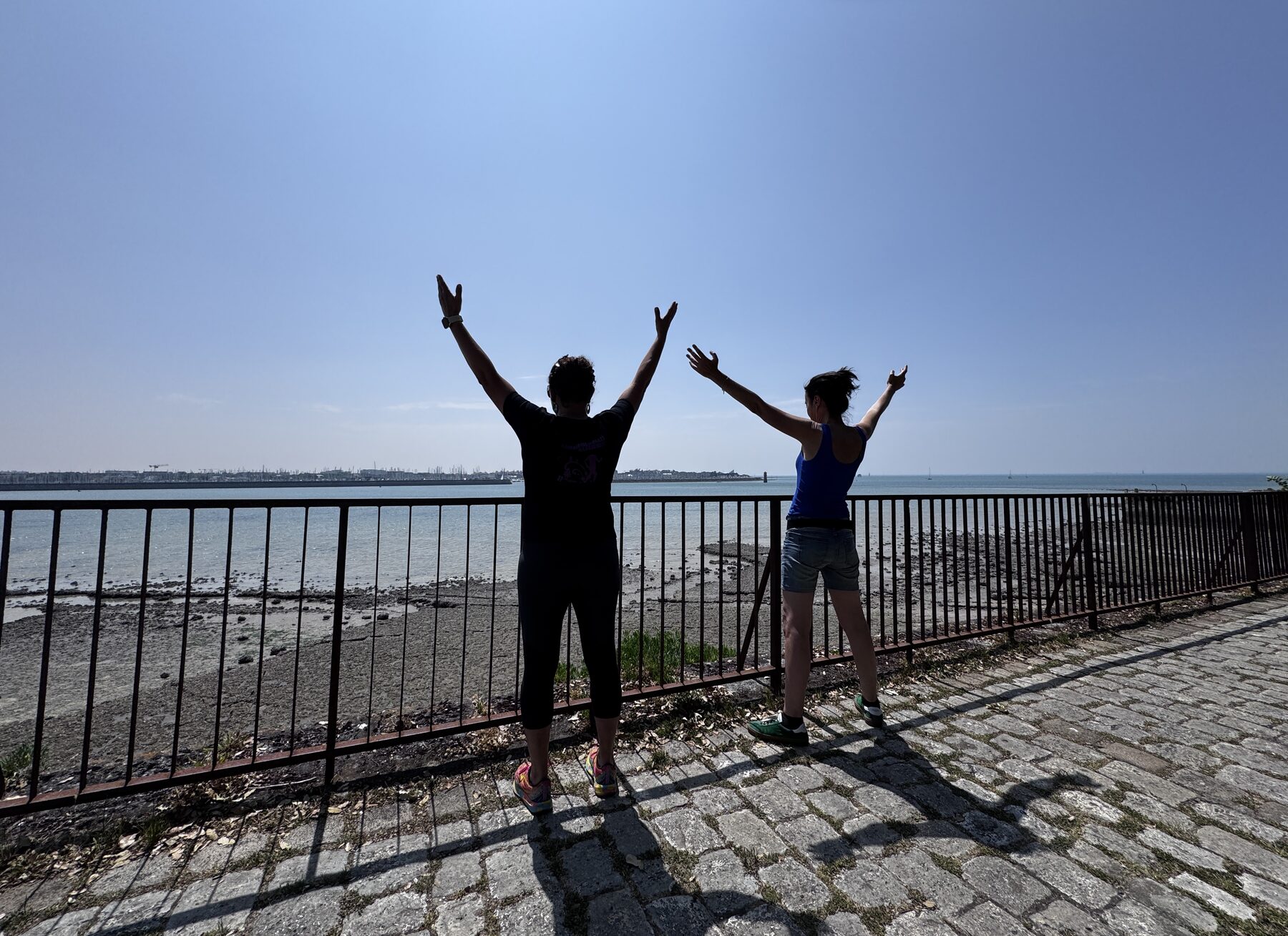 Deux silhouettes, bras levés face à la mer